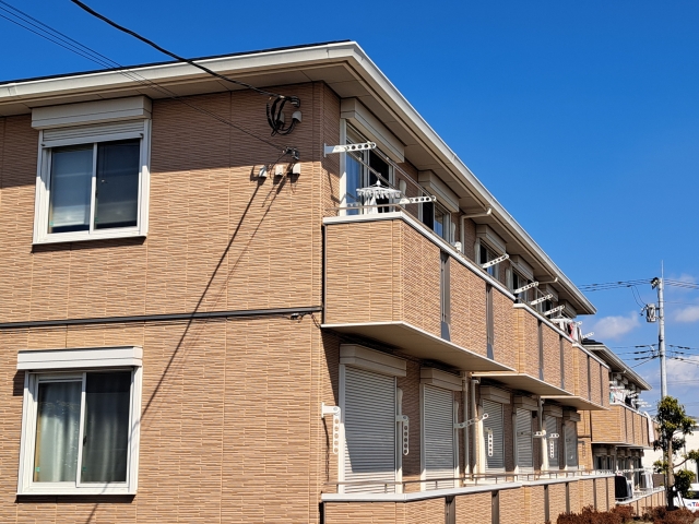 青空の下に建つ茶色の外壁を持つ集合住宅の建物
