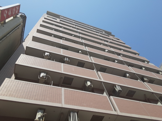 青空にそびえる茶色い外壁の高層マンション